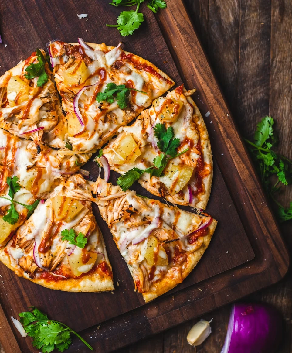 Pizza med kylling, ananas og koriander på et trebrett